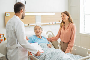 Woman standing with an older loved one and a doctor in the hospital, discussing how to advocate for a senior during hospitalization