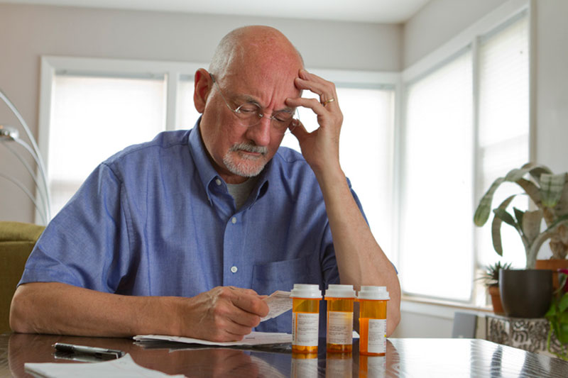 A senior man takes a look at his medications, a key step in helping reduce fall risks in seniors.