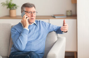 A senior man speaks on his phone, knowing AI scams against older adults are on the rise.