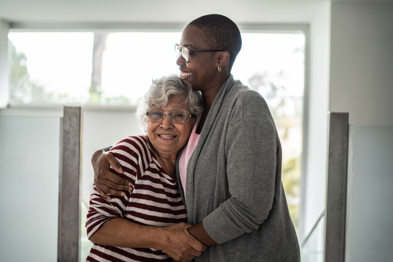 A woman embraces her aging mother and uses other tips to help relieve anxiety in seniors to improve her mother’s quality of life.